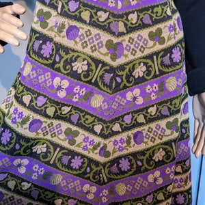 Puede incluir: Una falda de patr&oacute;n morado, verde y marr&oacute;n con un dise&ntilde;o floral. La falda est&aacute; hecha de tejido tejido y tiene una silueta ligeramente acampanada.