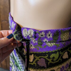 Puede incluir: Una falda de patr&oacute;n morado, verde y blanco con cierre de cremallera. La falda tiene un dise&ntilde;o floral y est&aacute; hecha de tejido tejido.