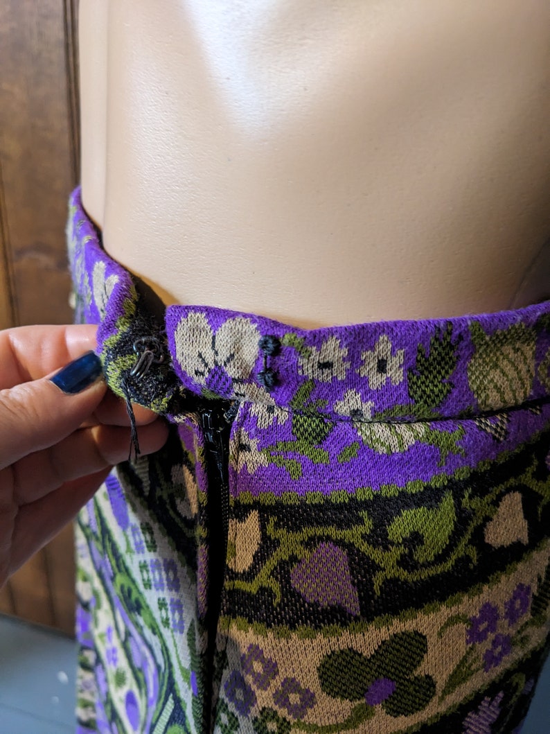 Puede incluir: Una falda de patr&oacute;n morado, verde y blanco con cierre de cremallera. La falda tiene un dise&ntilde;o floral y est&aacute; hecha de tejido tejido.