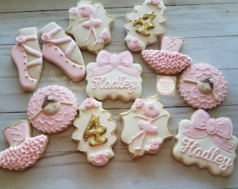 Puede incluir: Un conjunto de 11 galletas decoradas con temática de bailarina. Las galletas están decoradas con glaseado rosa, blanco y dorado. Las galletas incluyen una bailarina, un tutú, un lazo y el nombre "Hadley".