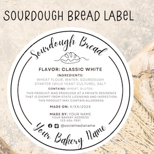 Puede incluir: Una etiqueta redonda blanca con texto negro para pan de masa madre. La etiqueta dice "Pan de masa madre" en una fuente de letra cursiva con un diseño de remolino. La etiqueta también incluye el sabor "Blanco Clásico", los ingredientes, contiene, hecho en, hecho por, y la información de las redes sociales.