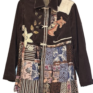 May include: Brown corduroy jacket with a patchwork design. The jacket features a collared neckline, long sleeves, and a button closure. The patchwork includes floral, paisley, and animal print fabrics, with decorative leaf and floral appliqués.
