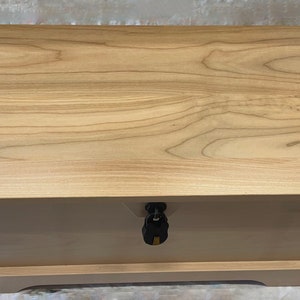 May include: A wooden storage chest with a hinged lid and a lock. The chest is made of light wood with a natural finish. The lid is closed and the lock is visible.