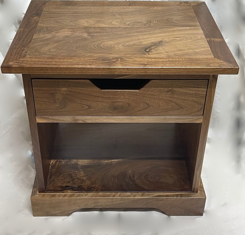 Puede incluir: Una mesa auxiliar de madera marr&oacute;n oscuro con un caj&oacute;n y un estante inferior. La mesa tiene un dise&ntilde;o simple y elegante y est&aacute; hecha de madera maciza.