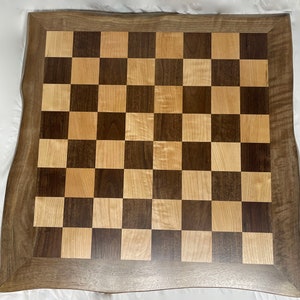 May include: A wooden chessboard with a dark brown and light wood checkered pattern. The board has a thick, dark brown frame with a natural wood edge.