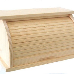 Puede incluir: Una caja de pan de madera con tapa enrollable. La caja está hecha de madera natural y tiene un color marrón claro.