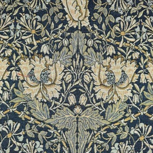 May include: A close-up of a fabric with a repeating floral pattern. The design features large, stylized flowers and foliage in shades of beige, tan, and green against a dark navy blue background. The pattern is symmetrical and detailed.