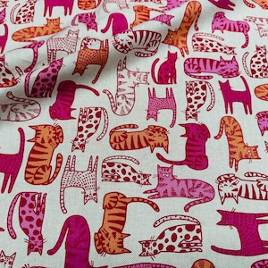 May include: Fabric with a repeating pattern of stylized cats in various poses. The cats are in shades of pink, orange, and white, with stripes, spots, and solid colors. The fabric has a light beige background.
