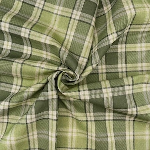 May include: A close-up shot of green plaid fabric. The fabric has a woven texture with a pattern of intersecting lines in shades of green and off-white. The fabric is gathered, showing the folds and texture, creating a classic plaid design.