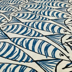 May include: A white textile with a repeating pattern of stylized blue fish. Each fish has a striped body and a black outline, creating a visually engaging design. The fish are arranged in a dense, overlapping manner.