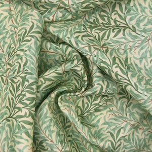 May include: A close-up of fabric featuring a repeating pattern of green willow leaves and branches on a cream background. The fabric is folded, creating shadows. The leaves are in varying shades of green.