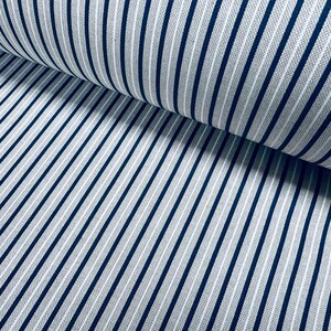 May include: A bolt of fabric featuring a classic pinstripe pattern with thin, dark navy blue vertical lines set against a light gray, textured background. The material is folded over itself, creating a soft curve that highlights the consistent spacing of the stripes across the surface of the textile.