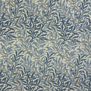 May include: A close-up of a fabric featuring a repeating pattern of blue and navy leaves and branches on a cream background. The leaves have a detailed, textured appearance, creating a natural, botanical design. The fabric is suitable for upholstery or home decor.