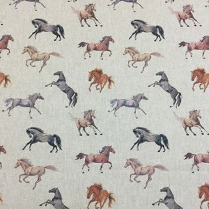 May include: A light beige fabric featuring a repeating pattern of horses in various poses and colors, including shades of brown, gray, and tan. The horses are depicted in motion, some galloping and others rearing, across the entire surface.