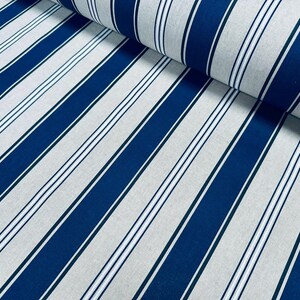 May include: A roll of fabric featuring a repeating pattern of wide navy blue stripes alternating with light gray sections. Each light gray section contains a central thin navy blue stripe flanked by two even thinner white lines, creating a classic striped design.