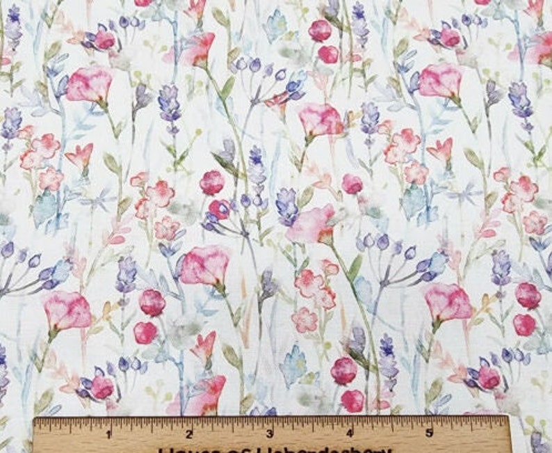 May include: Fabric with a floral watercolour design. The pattern features pink, purple, and blue flowers and foliage on a white background. The fabric has a delicate feel, with a ruler at the bottom.