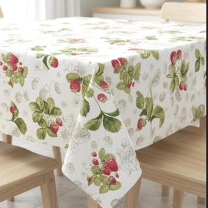 May include: A white tablecloth featuring a repeating pattern of red strawberries and green leaves. The design includes both detailed, colored illustrations of strawberry plants and faint, outline-style sketches of the same botanical elements.
