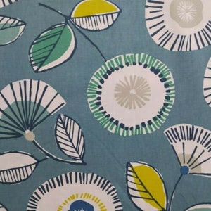Puede incluir: Primer plano de una tela con un estampado floral. El diseño presenta flores y hojas estilizadas en tonos de blanco, verde azulado, verde y amarillo sobre un fondo verde azulado. El patrón se repite en la tela, creando un diseño cohesivo.