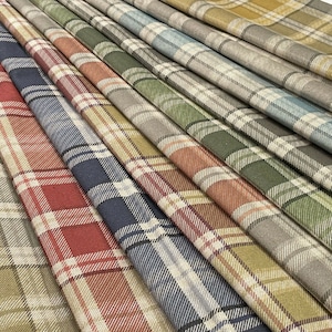 May include: A selection of plaid fabric swatches in a range of colours, such as red, blue, green, and yellow. The fabric features a traditional check pattern with white lines, giving a textured look. The swatches are arranged diagonally in a layered composition.