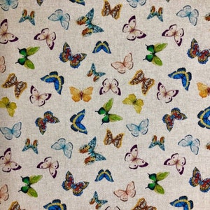 May include: A textile featuring a repeating design of butterflies in various sizes and colours. The butterflies are depicted in shades of blue, green, yellow, orange, and pink, set against a neutral backdrop. The wings display intricate patterns.