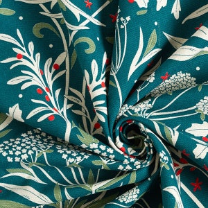 May include: A teal fabric featuring a repeating botanical pattern of white flowers, green leaves, and small red berries. The textile is gathered in a central swirl, showcasing the intricate floral print and the texture of the woven material.