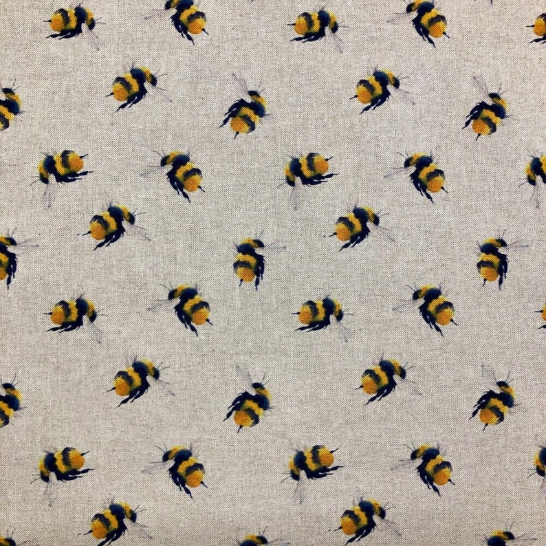 Puede incluir: Una tela con un patr&oacute;n repetitivo de abejorros amarillos y negros con alas transl&uacute;cidas. Las abejas est&aacute;n dispersas sobre un fondo beige neutro, creando un dise&ntilde;o caprichoso e inspirado en la naturaleza.