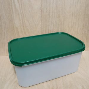 May include: A rectangular, white plastic container with a green lid. The lid is flat and fits snugly on the container. The container is designed for food storage and is made of durable plastic.