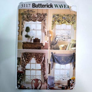 May include: A Butterick 3117 sewing pattern envelope featuring four variations of window valances and curtains. The images display draped fabric designs in floral and solid patterns, showcasing different styles of window treatments for home decor.