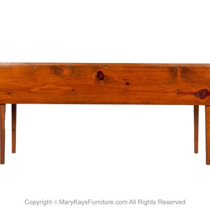 May include: A wooden drop leaf table with a natural wood finish and four legs. The table is closed and the leaves are down.