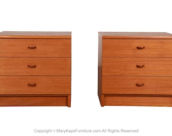 May include: Two matching wooden nightstands with three drawers each. The nightstands are made of light brown wood and have curved drawer pulls. The nightstands are set against a white background.