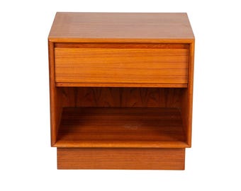 May include: A mid-century modern nightstand made of wood. The nightstand has a drawer at the top and an open shelf below. The wood has a warm, reddish-brown tone. The nightstand is rectangular and sits on a small base.