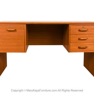 May include: A wooden desk with a warm, reddish-brown finish. The desk has two sets of drawers, one with a single drawer and the other with three drawers. The desk has a large open space in the middle for a chair and legs.