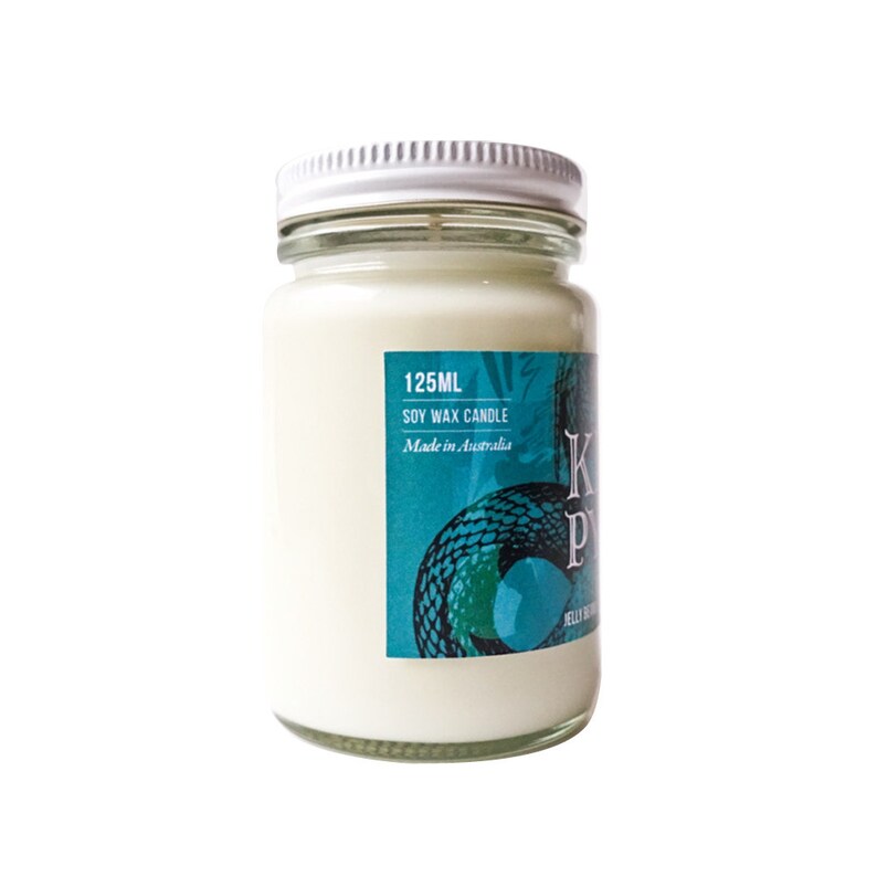 May include: A white soy wax candle in a glass jar with a teal and green label. The label says "125ML SOY WAX CANDLE Made in Australia" and features a snake design. The candle is labeled "Kookaburra Pyjama"