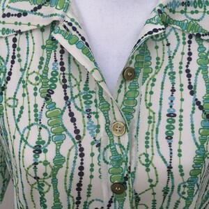 May include: A white button-up shirt with a green, blue, and black abstract pattern of beads and circles.