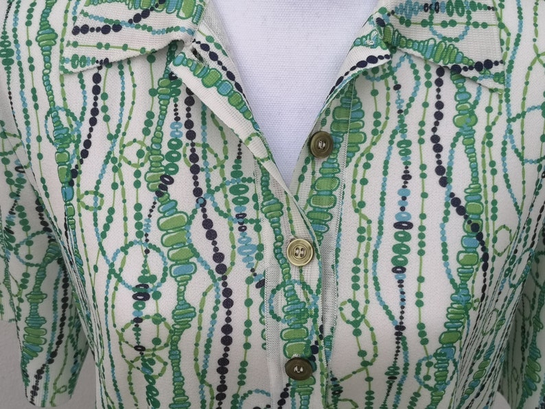 May include: A white button-up shirt with a green, blue, and black abstract pattern of beads and circles.
