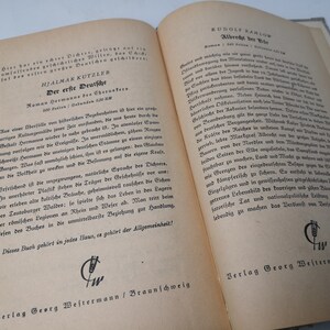 May include: A close-up of two open books with text in German. The book on the left is titled "Der erste Deutsche" by Hjalmar Kutzler. The book on the right is titled "Albrecht bey der" by Rudolf Ramlow. Both books are published by Verlag Georg Westermann in Braunschweig.