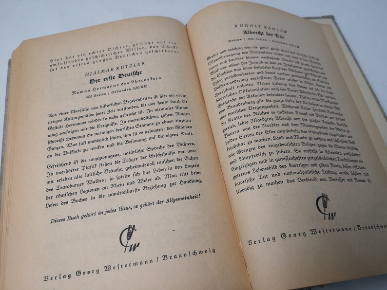 May include: A close-up of two open books with text in German. The book on the left is titled "Der erste Deutsche" by Hjalmar Kutzler. The book on the right is titled "Albrecht bey der" by Rudolf Ramlow. Both books are published by Verlag Georg Westermann in Braunschweig.