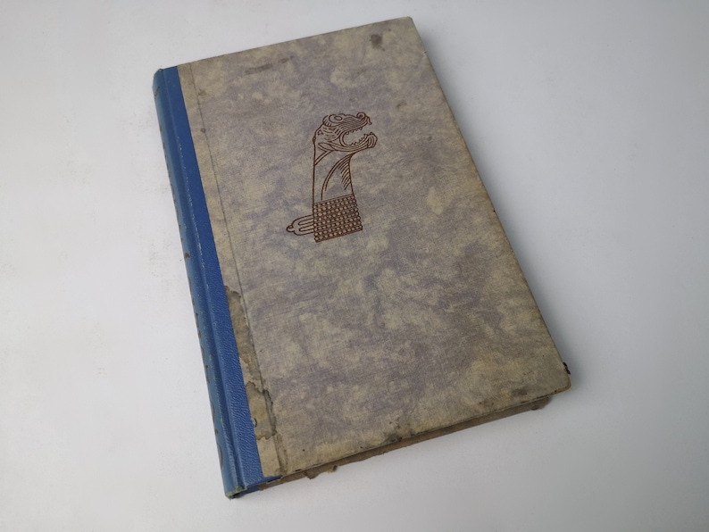 May include: A vintage hardcover book with a blue spine and a brown illustration of a stylized animal head on the front cover.