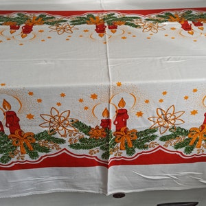 Può includere: Tovaglia bianca con un bordo rosso e verde che presenta un motivo ripetitivo di candele, stelle e disegni floreali. La tovaglia è perfetta per una cena di Natale o un ritrovo festivo.