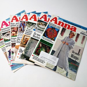 May include: A stack of five German-language magazines titled "Anna" with a focus on knitting and crocheting. The cover of the top magazine features a woman wearing a grey knitted cardigan and skirt. The text on the cover reads "burda SPASS AN HANDARBEITEN" and "Die neuen Winter-trends".