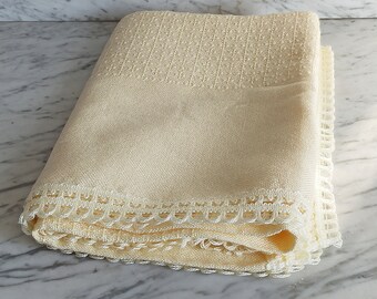 May include: Folded cream-colored linen towel with a textured top section and a decorative scalloped lace trim along the edge. The towel is folded neatly, showcasing the detailed craftsmanship and soft color.