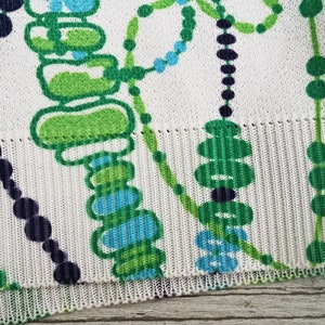 May include: White fabric with a green, blue, and black abstract pattern. The pattern features circles, lines, and shapes.