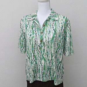 May include: White short-sleeved shirt with a green, blue, and white beaded pattern.