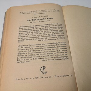 May include: A vintage book titled "Die Infel der wei&szlig;en G&ouml;ttin" by Carola Schiel. The book cover features a decorative design with a wheat stalk symbol and the text "Verlag Georg Westermann / Braunschweig".