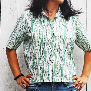 May include: A white short-sleeved shirt with a green and blue abstract pattern. The shirt has a collar and a button closure.
