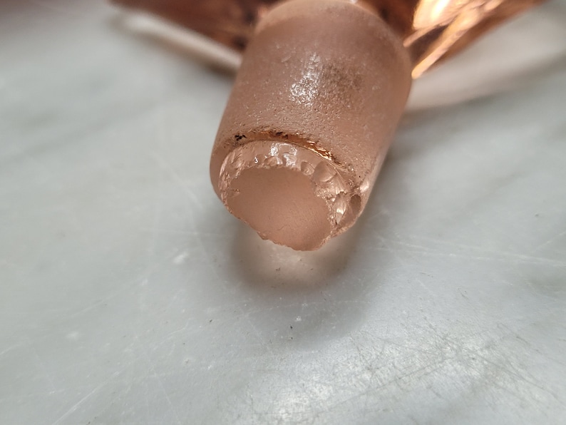 May include: Close-up of a clear glass bottle stopper with a gold rim. The stopper has a slightly chipped edge.