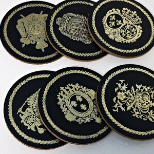 Könnte beinhalten: Satz mit sechs schwarzen Untersetzern mit goldfarbenen Designs. Jeder Untersetzer zeigt ein anderes, kunstvolles Design mit königlichem Thema.