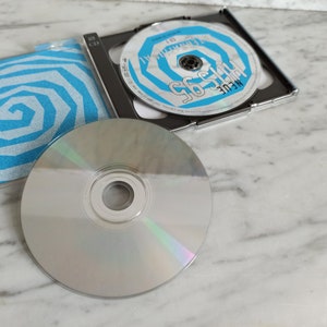 May include: A silver CD with a blue and white spiral design on the cover. The CD is titled "The 95's" and the artist is "MEULE".