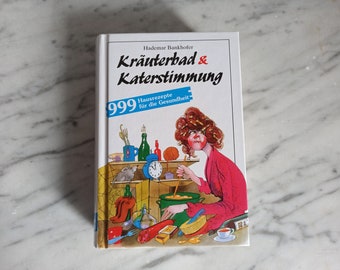 May include: A book cover featuring a cartoon illustration of a woman in a red robe stirring a pot of food. The book title is "Krauterbad & Katerstimmung" with the subtitle "999 Hausrezepte fur die Gesundheit".