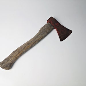 May include: A wooden-handled axe with a red metal head. The axe is in good condition and has a worn, rustic look.